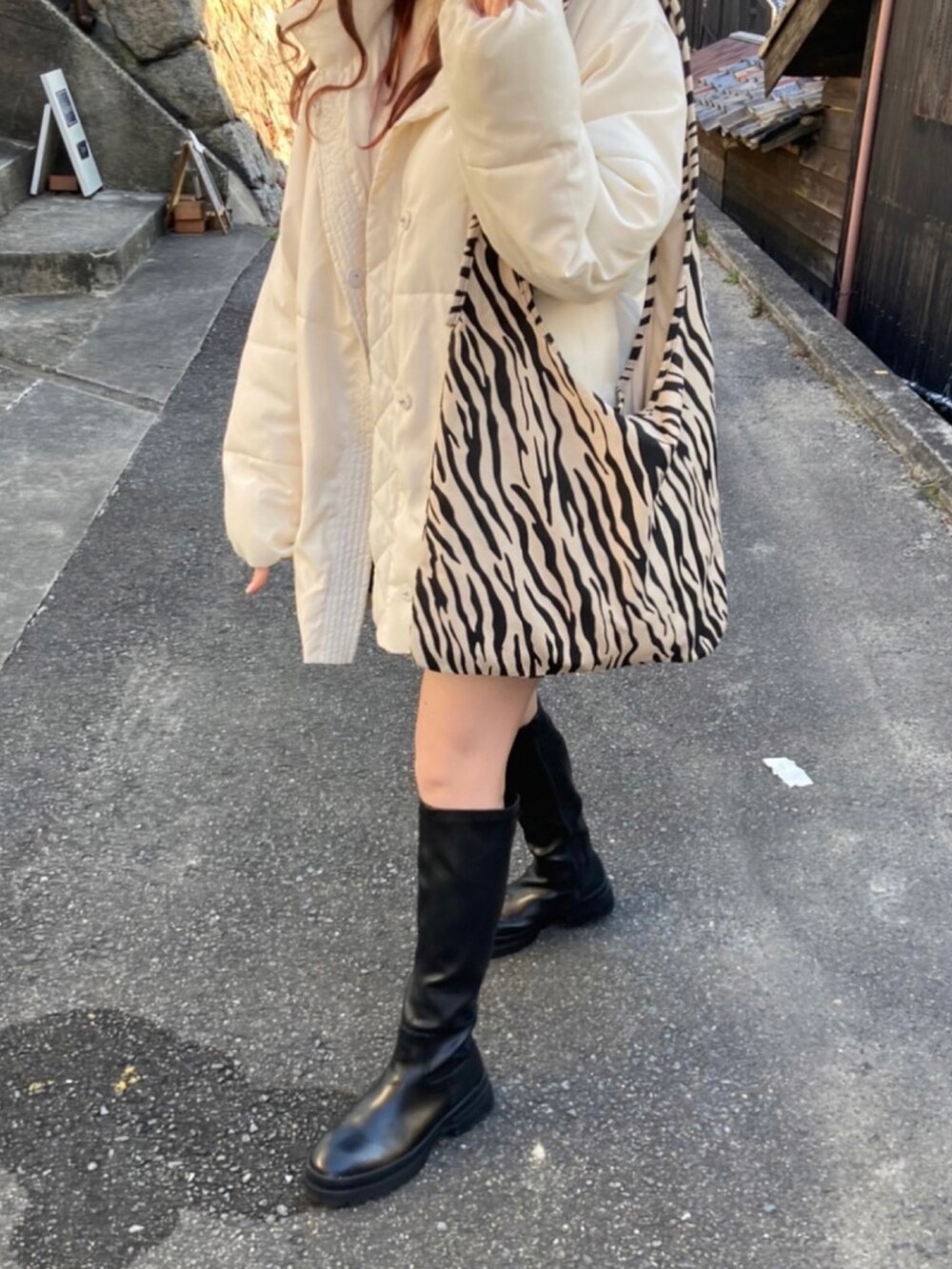 ホワイト系のダウンジャケット/コート、ブラック系のその他パンツ、ブラック系のブーツを着用したレディースの冬コーディネートの2枚目の写真