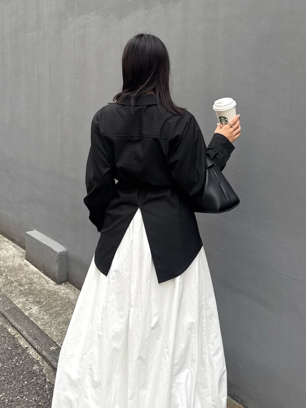 グレー系のシャツ/ブラウス、ホワイト系のスカート、ブラック系のトートバッグを着用したレディースの秋コーディネートの4枚目の写真