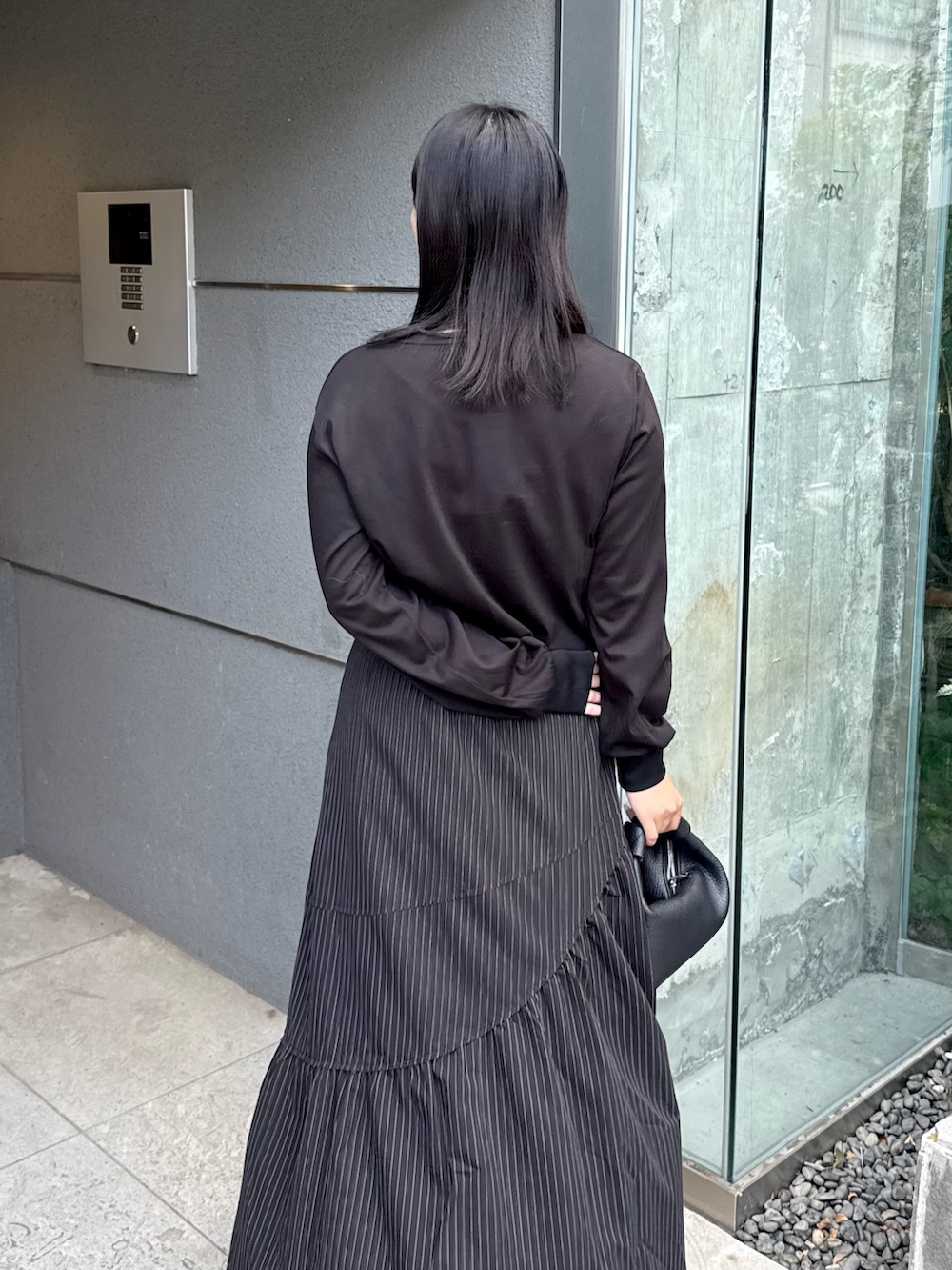 ブラック系のTシャツ/カットソー、ブラック系のスカート、ブラック系のトートバッグを着用したレディースの秋コーディネートの5枚目の写真