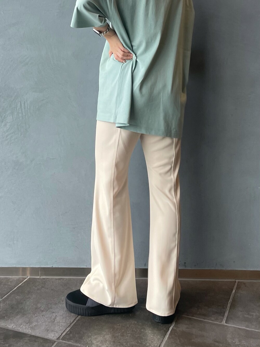 グリーン系のTシャツ/カットソー、ホワイト系のスラックス、ブラック系のスニーカーを着用したレディースの春コーディネートの4枚目の写真