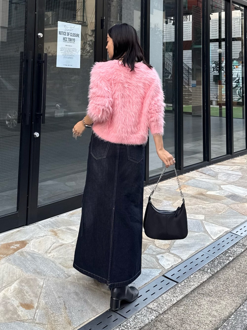ピンク系のニット/セーター、ブルー系のデニムスカート、ブラック系のショルダーバッグを着用したレディースの秋コーディネートの3枚目の写真
