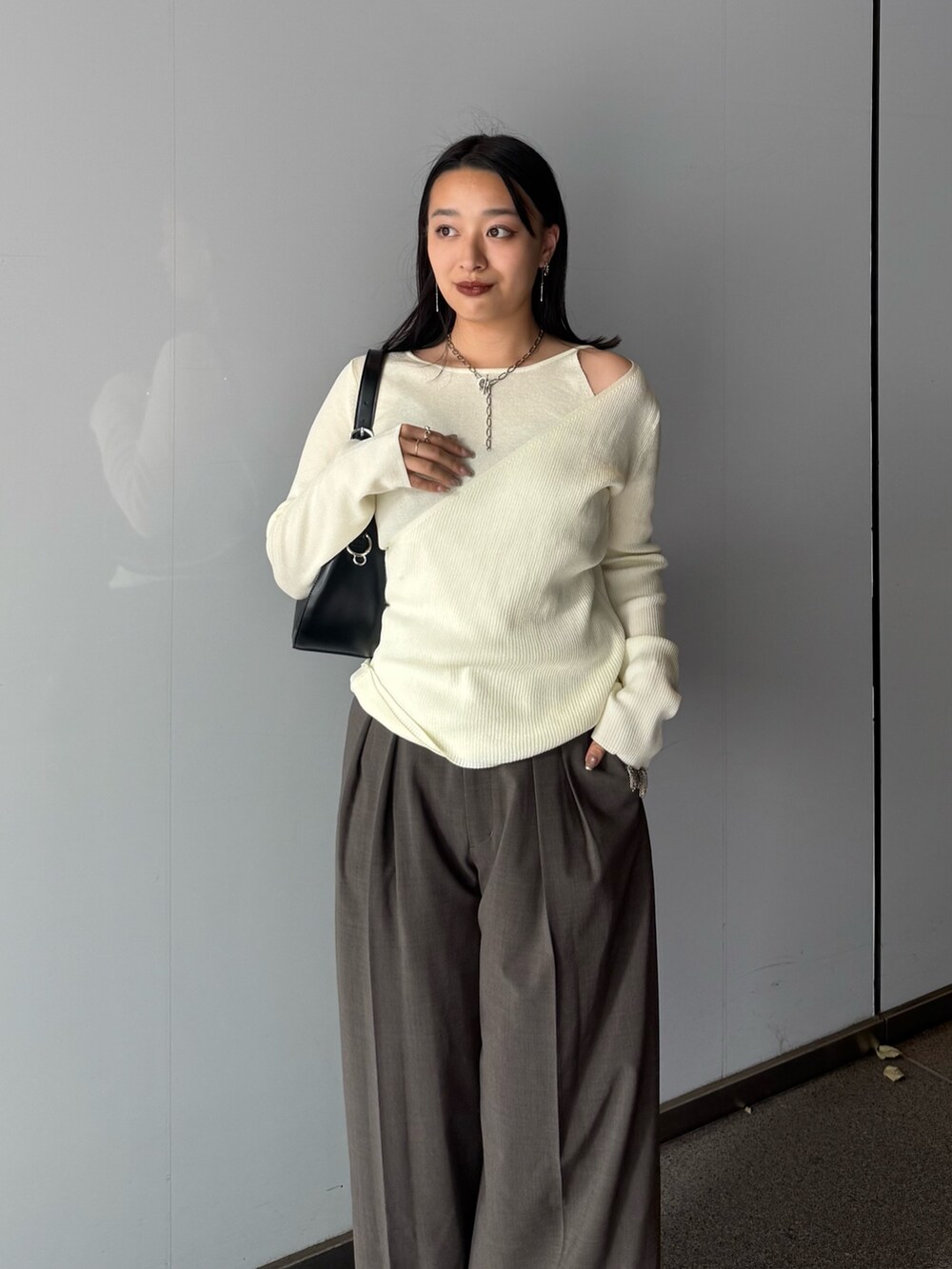 ホワイト系のニット/セーター、ブラウン系のスラックス、ブラック系のブーツを着用したレディースの夏コーディネートの3枚目の写真