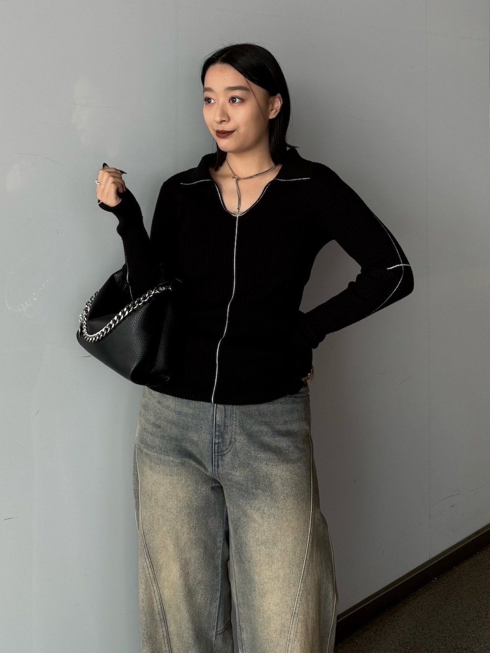 ブラック系のニット/セーター、ブルー系のデニムパンツ、ブラック系のトートバッグを着用したレディースの春コーディネートの3枚目の写真