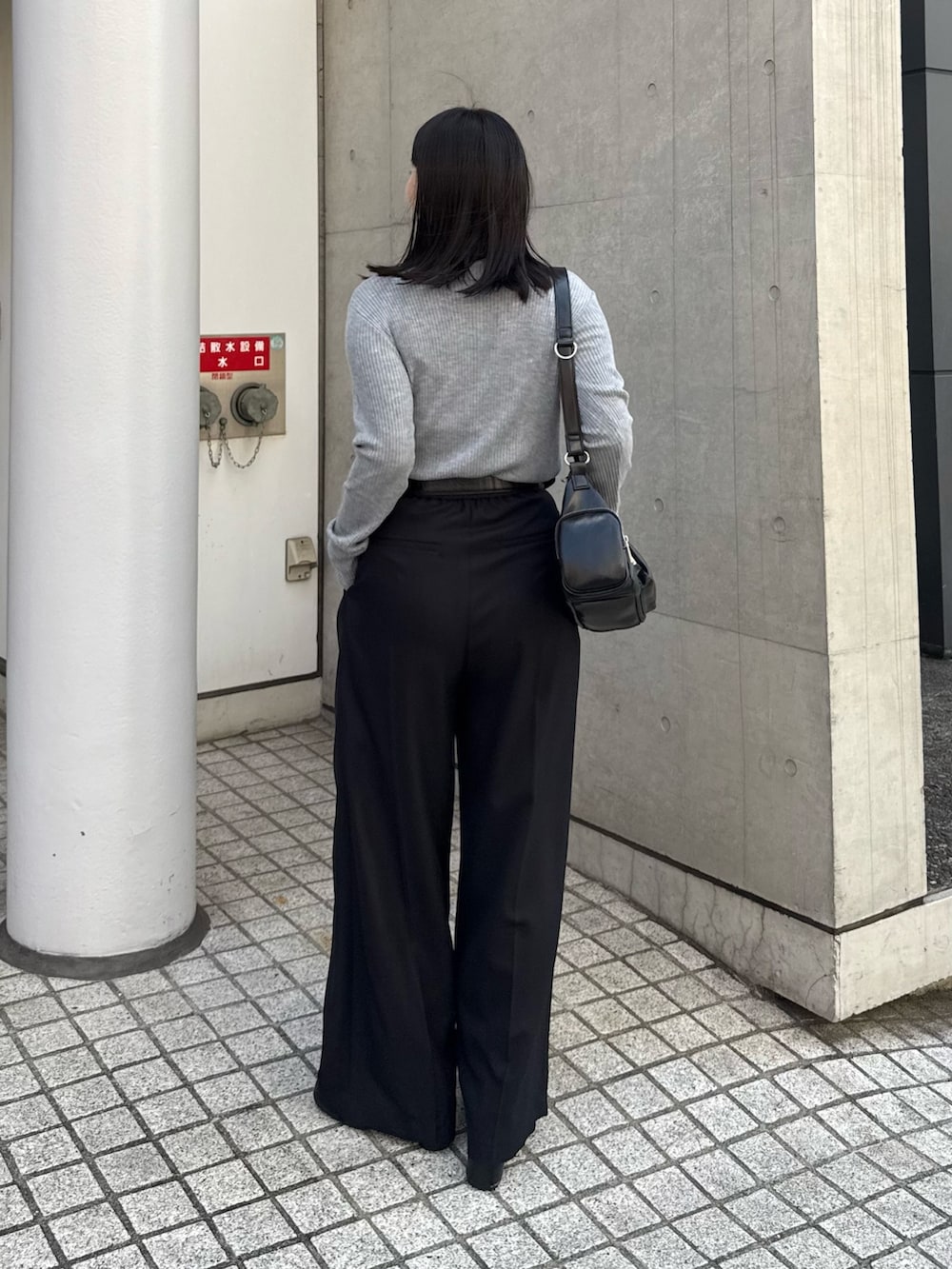 グレー系のニット/セーター、ブラック系のスラックス、ブラック系のショルダーバッグを着用したレディースの秋コーディネートの2枚目の写真