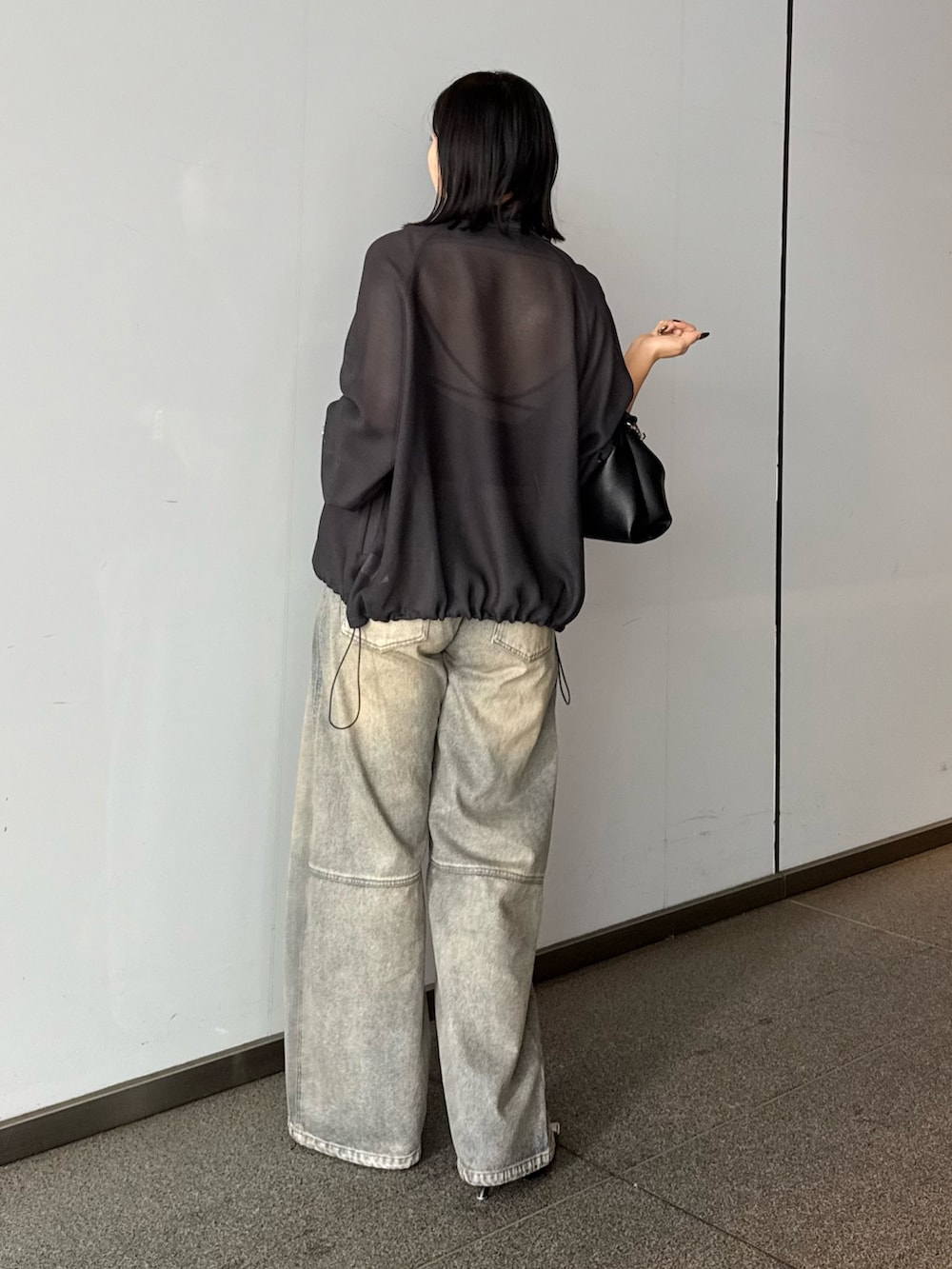 グレー系のブルゾン、ブルー系のデニムパンツ、ブラック系のトートバッグを着用したレディースの春コーディネートの2枚目の写真