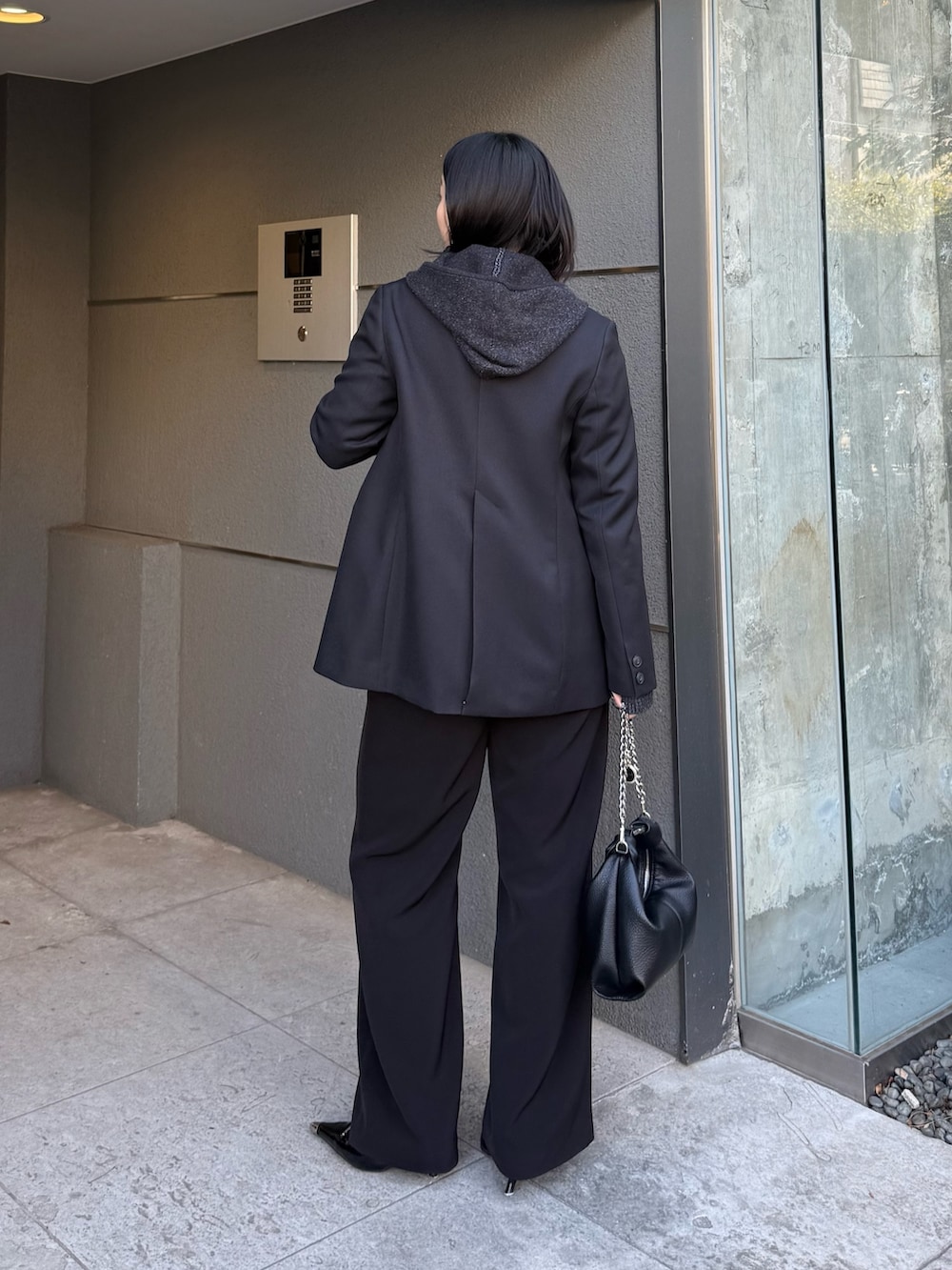 ブラック系のテーラードジャケット、ブラック系のニット/セーター、ブラック系のトートバッグを着用したレディースの冬コーディネートの3枚目の写真