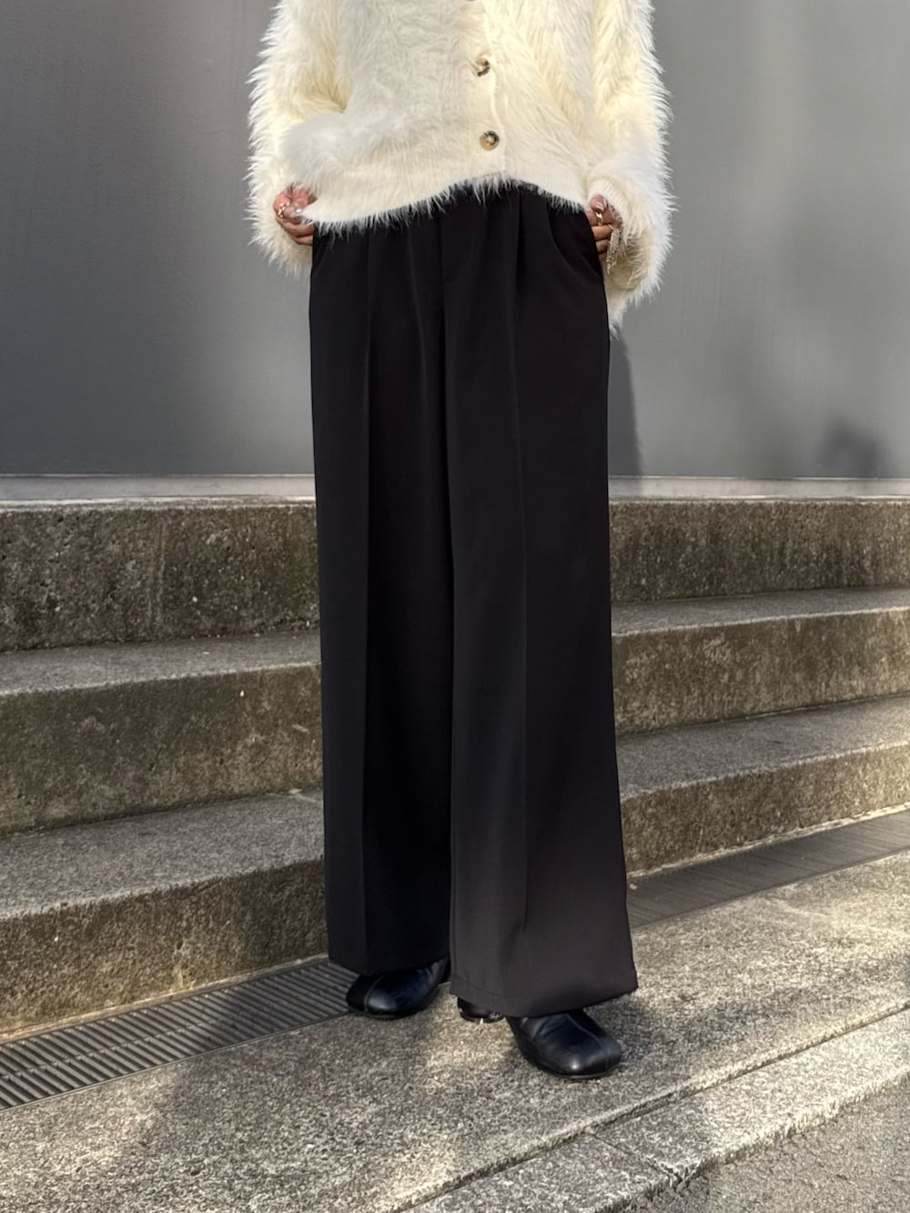 ブラック系のスラックス、ブラック系のブーツ、ホワイト系のカーディガン/ボレロを着用したレディースの夏コーディネートの5枚目の写真