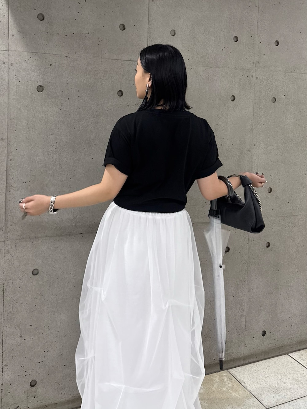 ブラック系のTシャツ/カットソー、ホワイト系のスカート、ブラック系のトートバッグを着用したレディースの春コーディネートの4枚目の写真