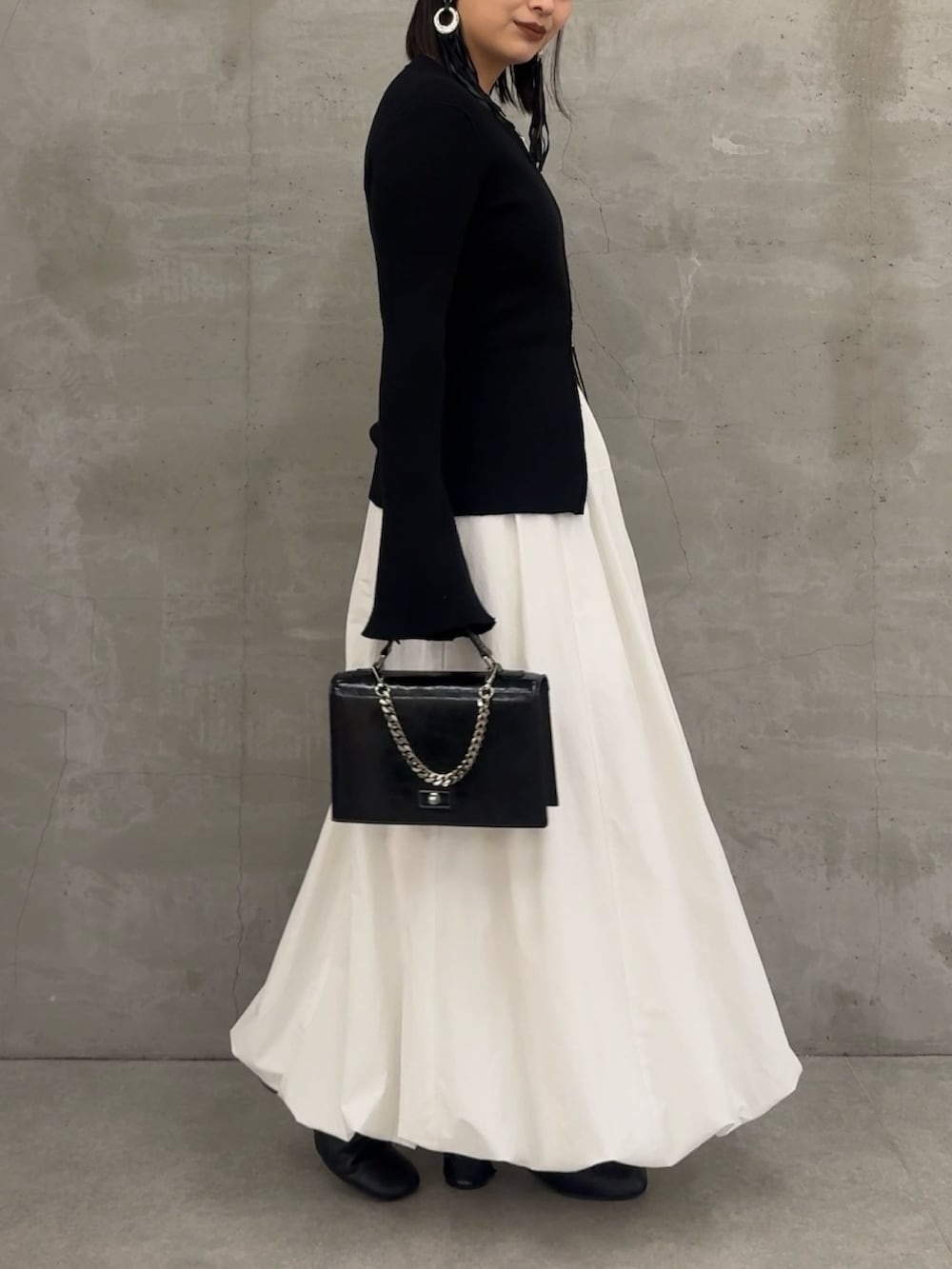 ブラック系のニット/セーター、ブラック系のショルダーバッグを着用したレディースの冬コーディネートの2枚目の写真