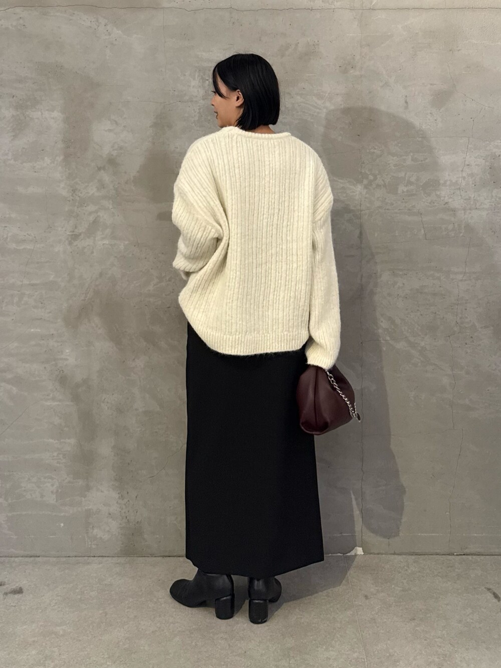 ホワイト系のニット/セーター、ブラック系のスカート、レッド系のトートバッグを着用したレディースの秋コーディネートの3枚目の写真