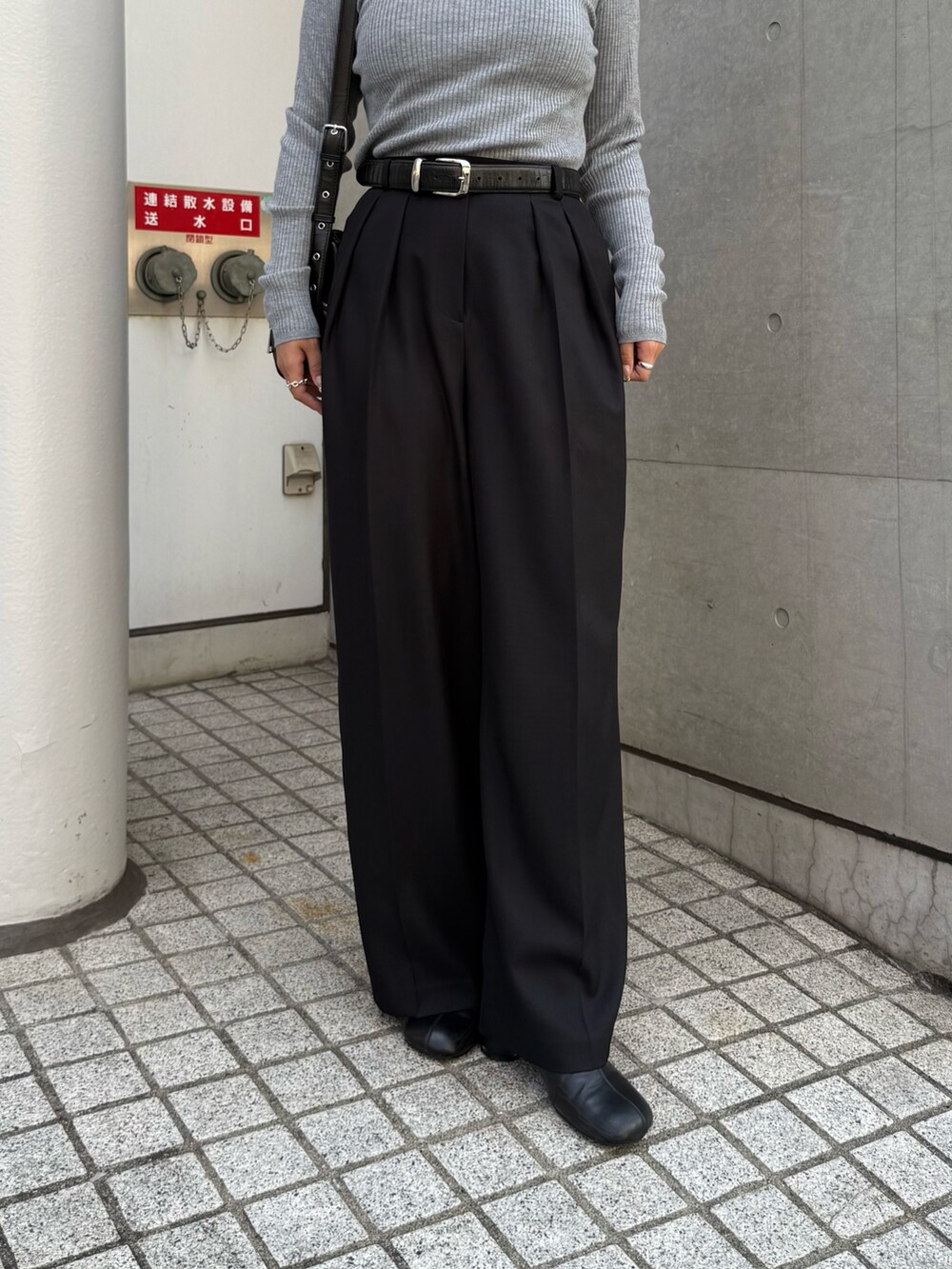 グレー系のニット/セーター、ブラック系のスラックス、ブラック系のショルダーバッグを着用したレディースの秋コーディネートの4枚目の写真