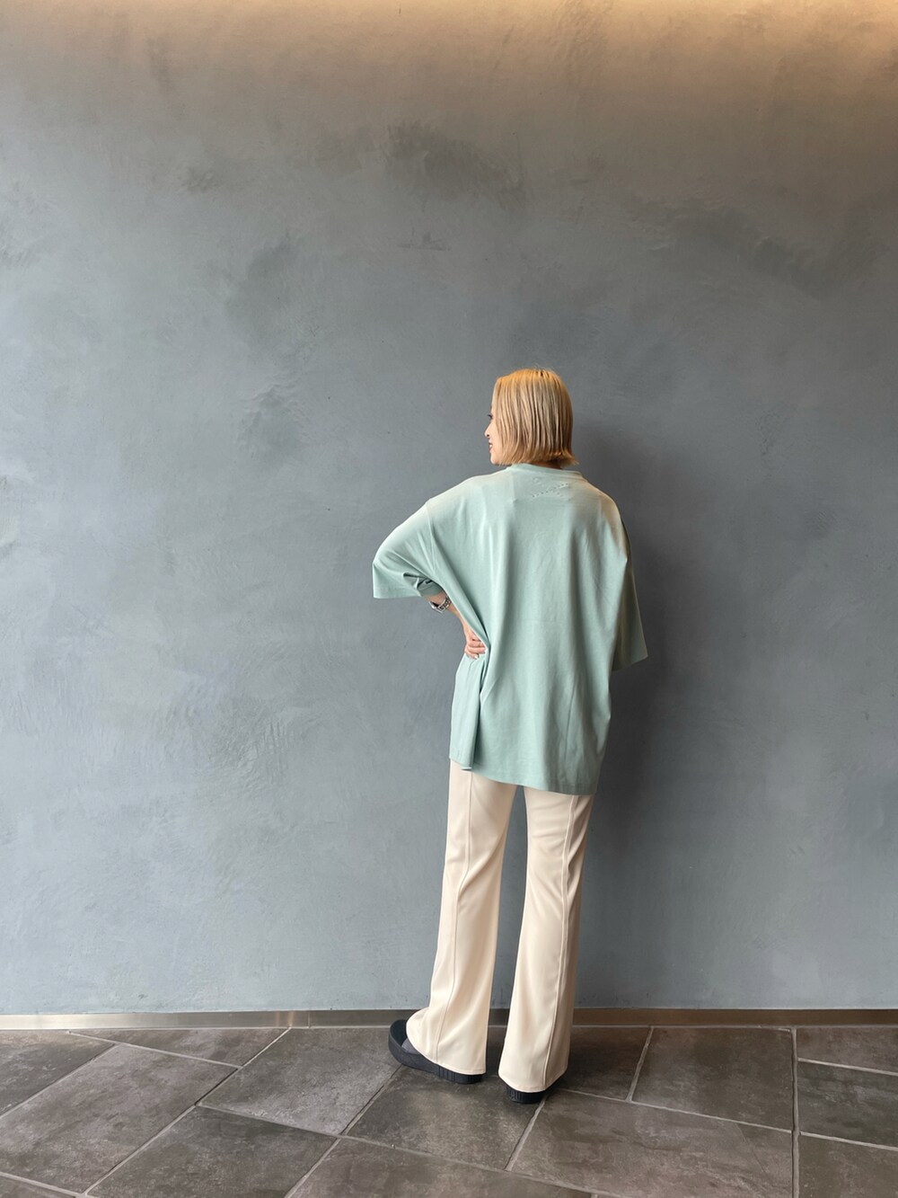 グリーン系のTシャツ/カットソー、ホワイト系のスラックス、ブラック系のスニーカーを着用したレディースの春コーディネートの3枚目の写真