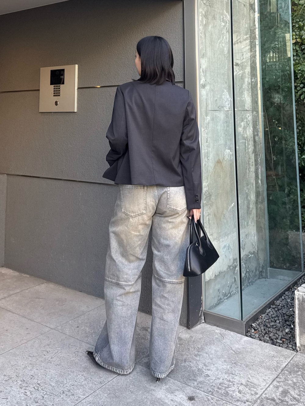 ブラック系のテーラードジャケット、ブルー系のデニムパンツ、ブラック系のショルダーバッグを着用したレディースの冬コーディネートの3枚目の写真