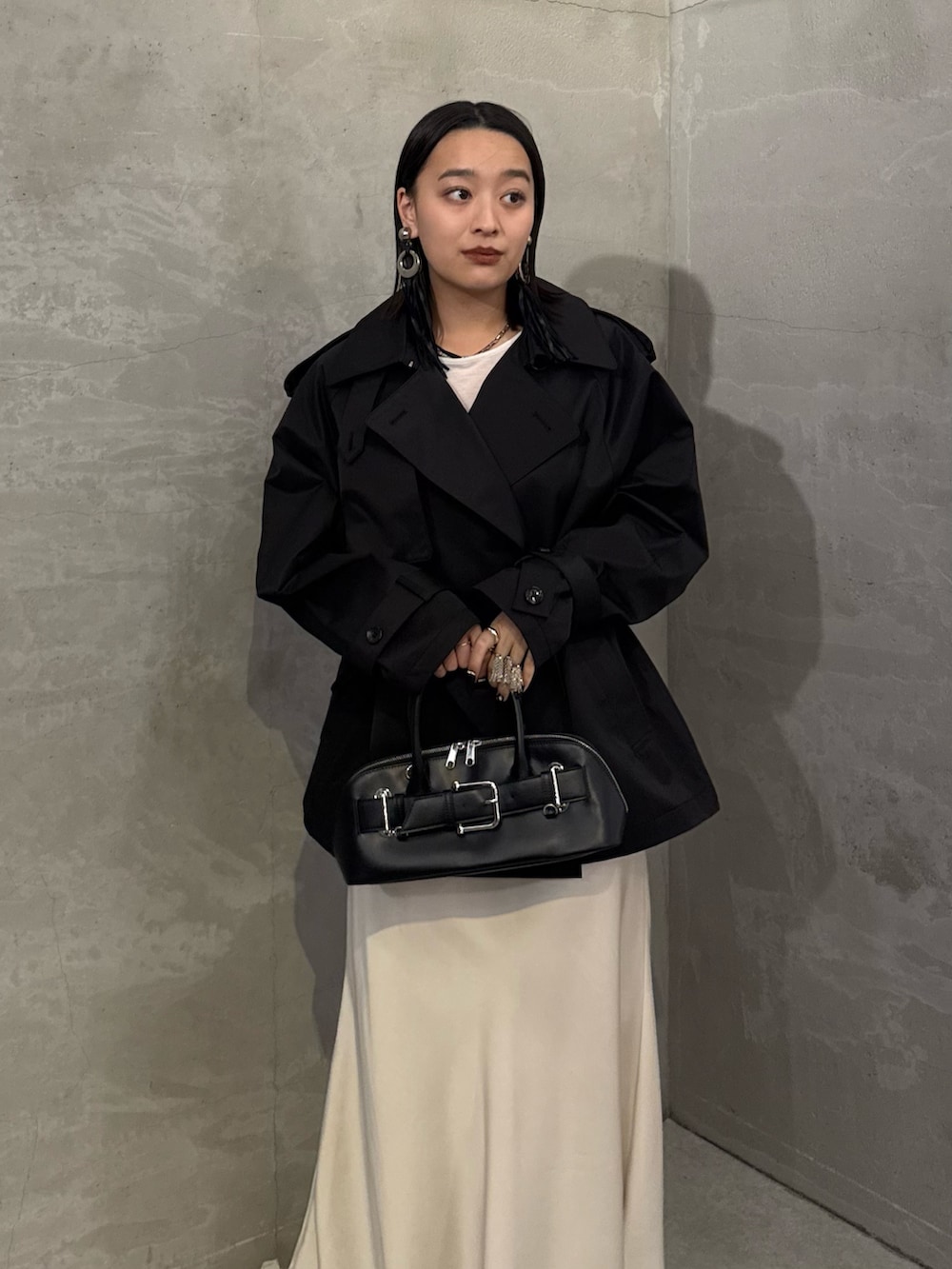 ブラック系のトレンチコート、ホワイト系のスカート、ブラック系のショルダーバッグを着用したレディースの冬コーディネートの4枚目の写真