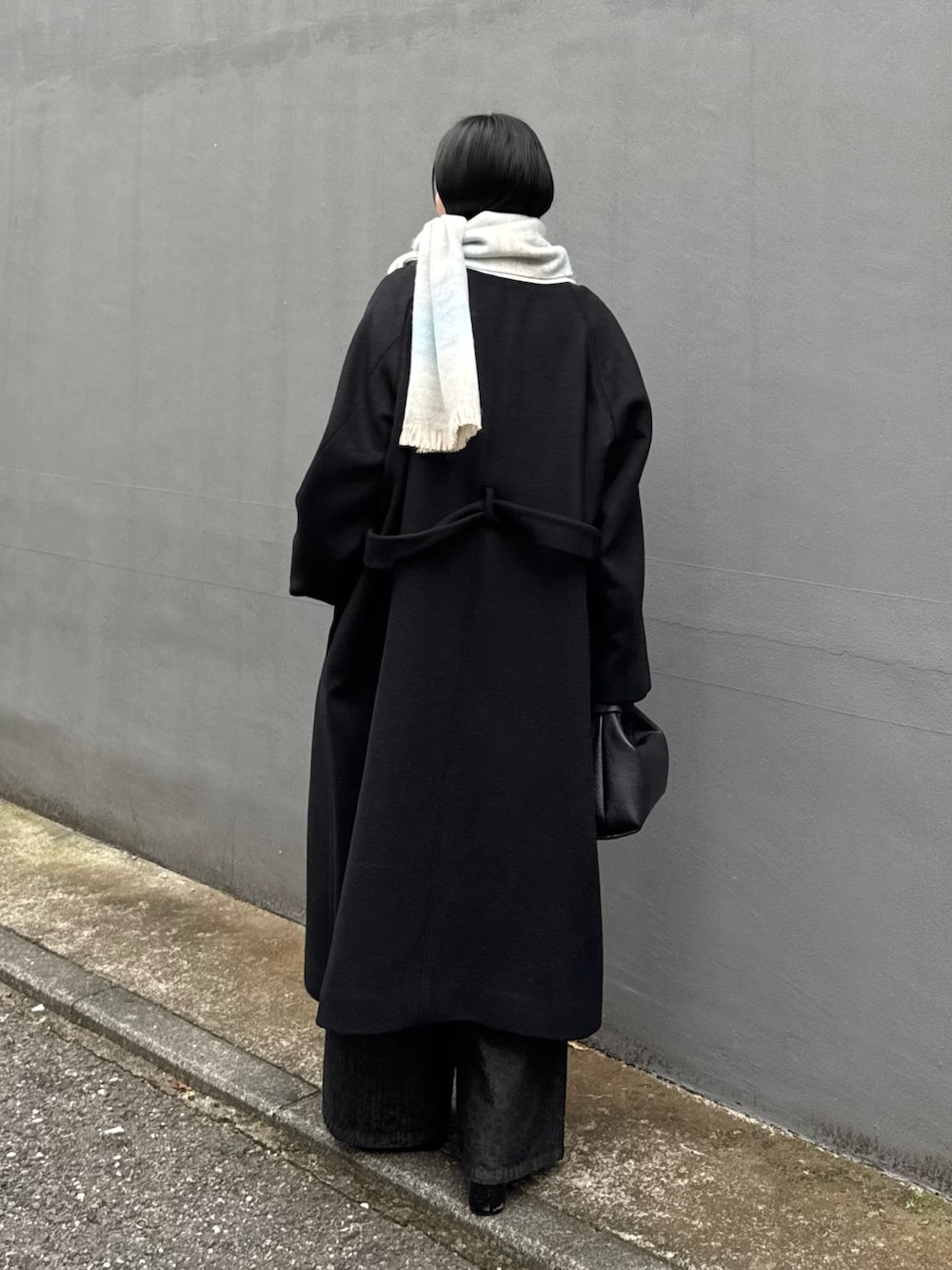 ブラック系のチェスターコート、ブラック系のトートバッグ、ブラック系のデニムパンツを着用したレディースの秋コーディネートの2枚目の写真