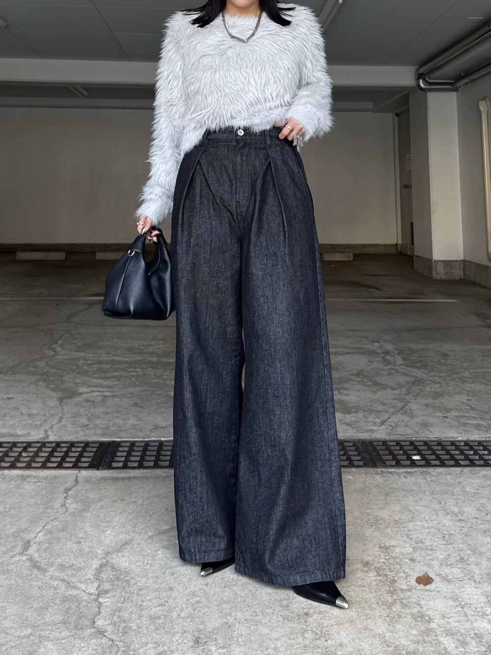 ブラック系のデニムパンツ、ブラック系のトートバッグ、グレー系のニット/セーターを着用したレディースの秋コーディネートの3枚目の写真