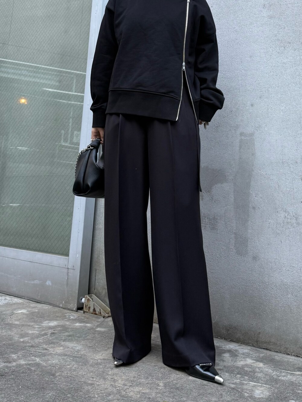 ブラック系のTシャツ/カットソー、ブラック系のスラックス、ブラック系のトートバッグを着用したレディースの冬コーディネートの6枚目の写真