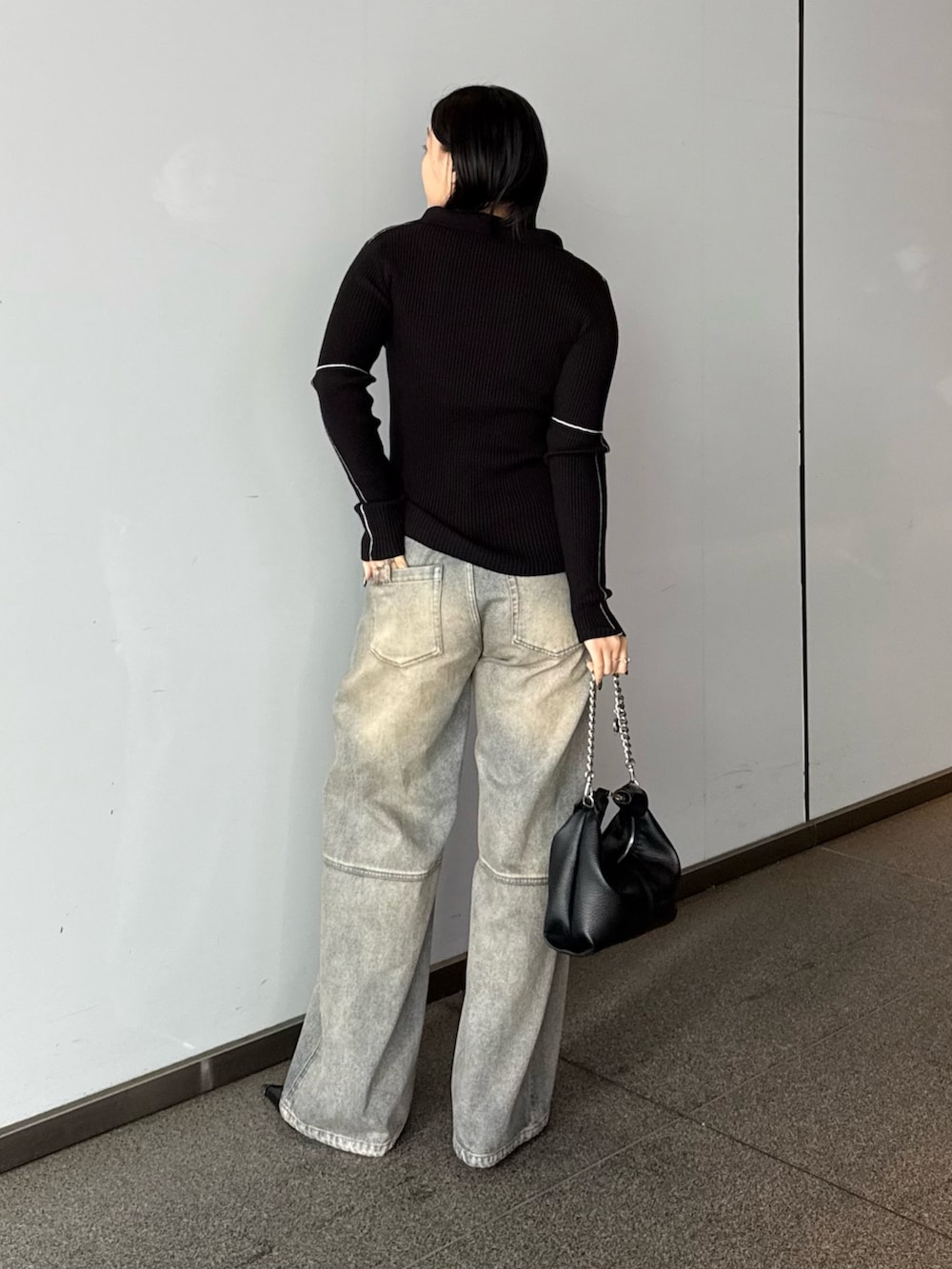 ブラック系のニット/セーター、ブルー系のデニムパンツ、ブラック系のトートバッグを着用したレディースの春コーディネートの2枚目の写真