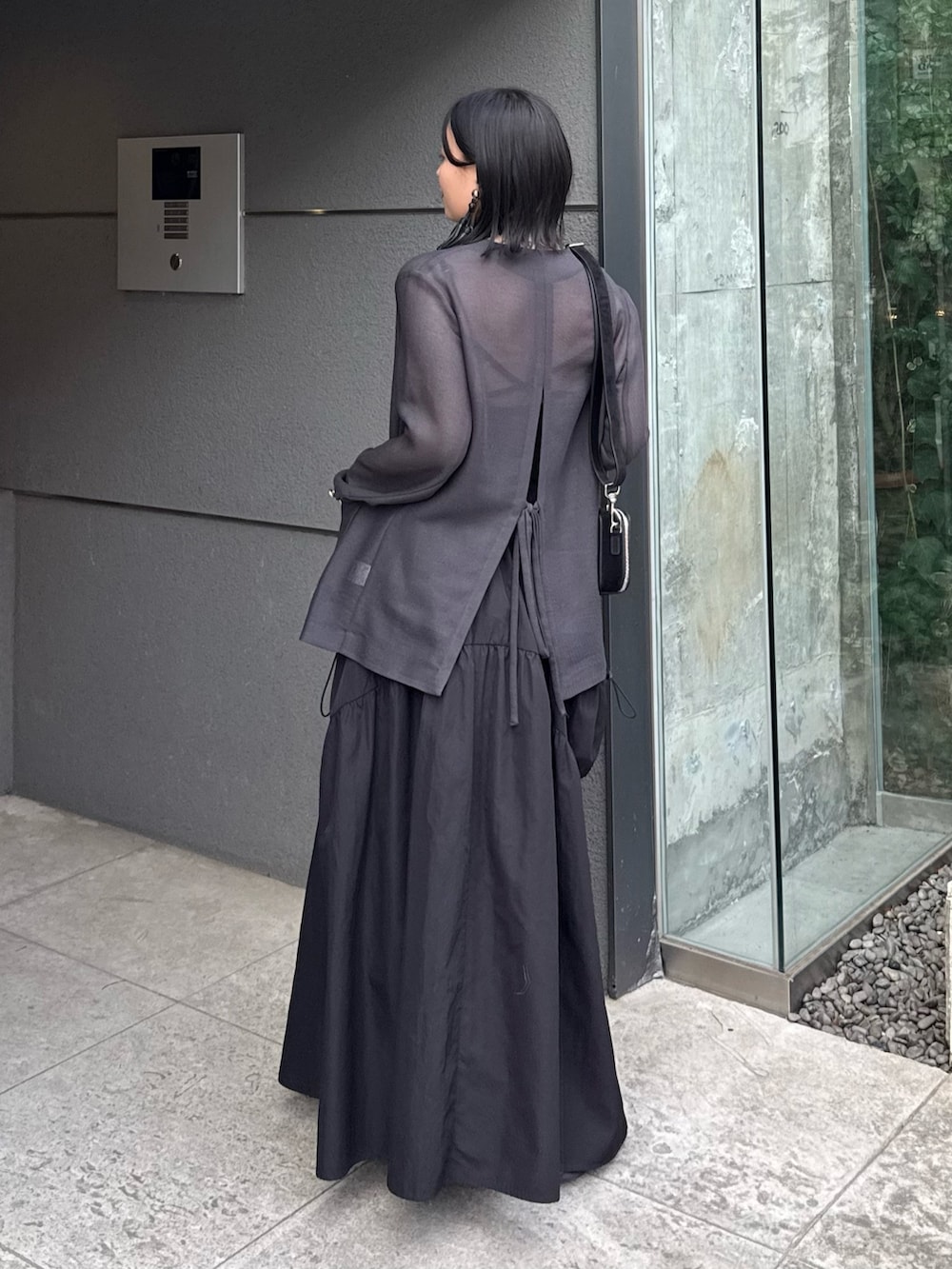 グレー系のテーラードジャケット、ブラック系のタンクトップ、ブラック系のスカートを着用したレディースの春コーディネートの3枚目の写真