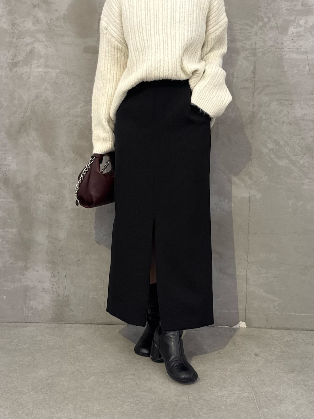ホワイト系のニット/セーター、ブラック系のスカート、レッド系のトートバッグを着用したレディースの秋コーディネートの6枚目の写真