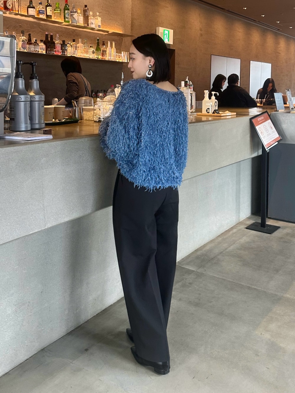 ブルー系のTシャツ/カットソー、ブラック系のスラックス、ブラック系のショルダーバッグを着用したレディースの春コーディネートの4枚目の写真