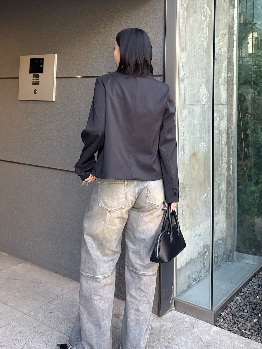 ブラック系のテーラードジャケット、ブルー系のデニムパンツ、ブラック系のショルダーバッグを着用したレディースの冬コーディネートの5枚目の写真