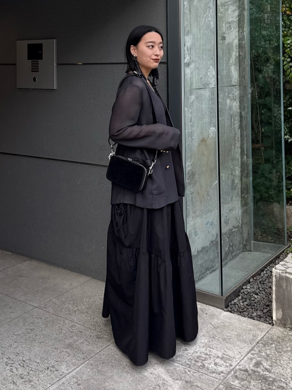 グレー系のテーラードジャケット、ブラック系のタンクトップ、ブラック系のスカートを着用したレディースの春コーディネートの2枚目の写真