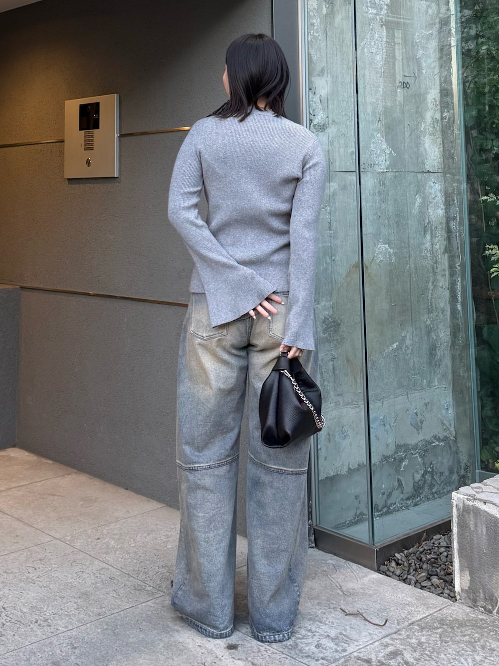 グレー系のニット/セーター、ブルー系のデニムパンツ、ブラック系のトートバッグを着用したレディースの冬コーディネートの2枚目の写真