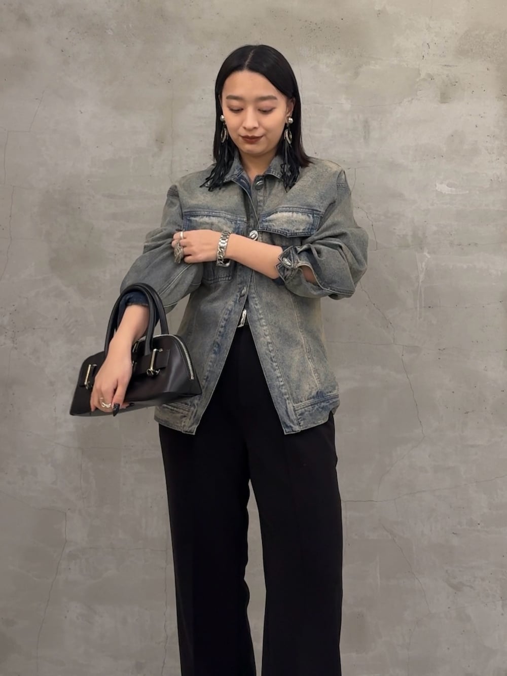 ブラック系のデニムジャケット、ブラック系のスラックス、ブラック系のショルダーバッグを着用したレディースの冬コーディネートの3枚目の写真