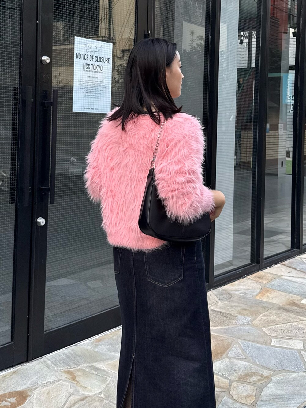 ピンク系のニット/セーター、ブルー系のデニムスカート、ブラック系のショルダーバッグを着用したレディースの秋コーディネートの4枚目の写真