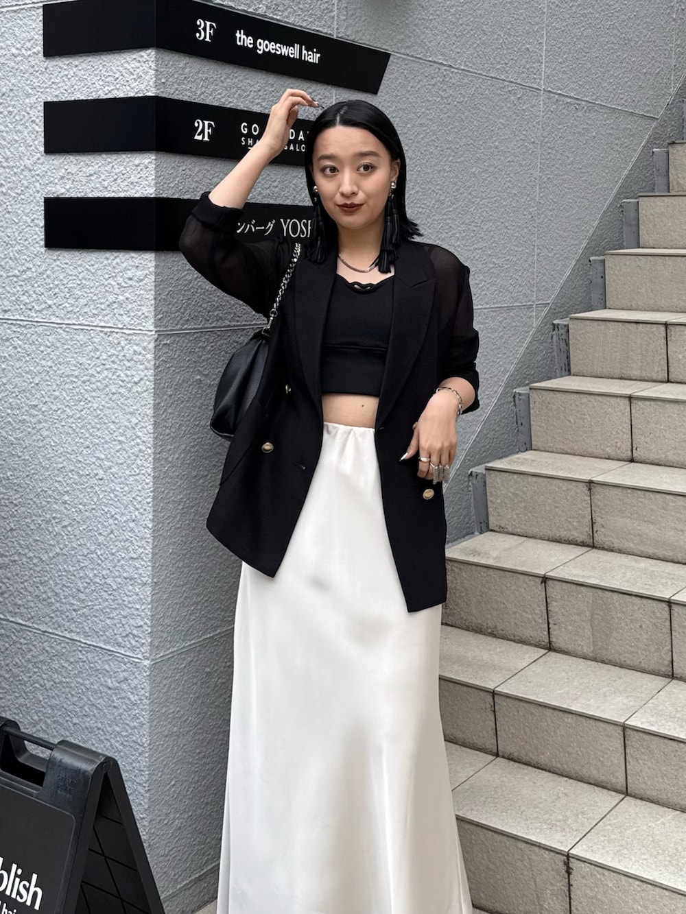 ブラック系のテーラードジャケット、ホワイト系のスカート、ブラック系のタンクトップを着用したレディースの春コーディネートの2枚目の写真