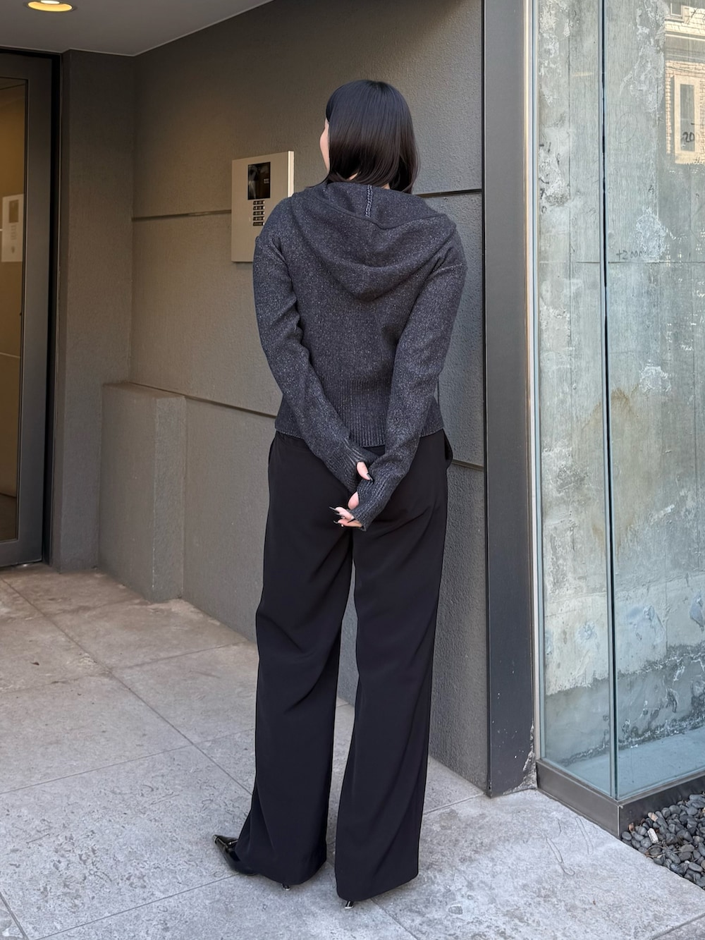 ブラック系のニット/セーター、ブラック系のスラックス、ブラック系のベルトを着用したレディースの冬コーディネートの2枚目の写真