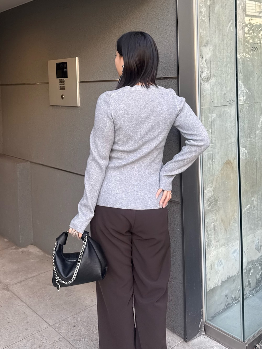 グレー系のニット/セーター、ブラウン系のスラックス、ブラック系のトートバッグを着用したレディースの冬コーディネートの4枚目の写真