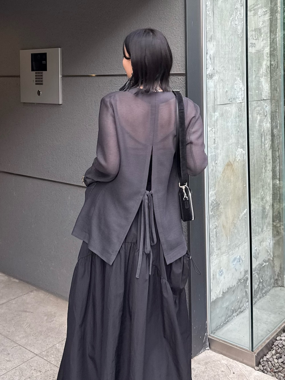 グレー系のテーラードジャケット、ブラック系のタンクトップ、ブラック系のスカートを着用したレディースの春コーディネートの5枚目の写真