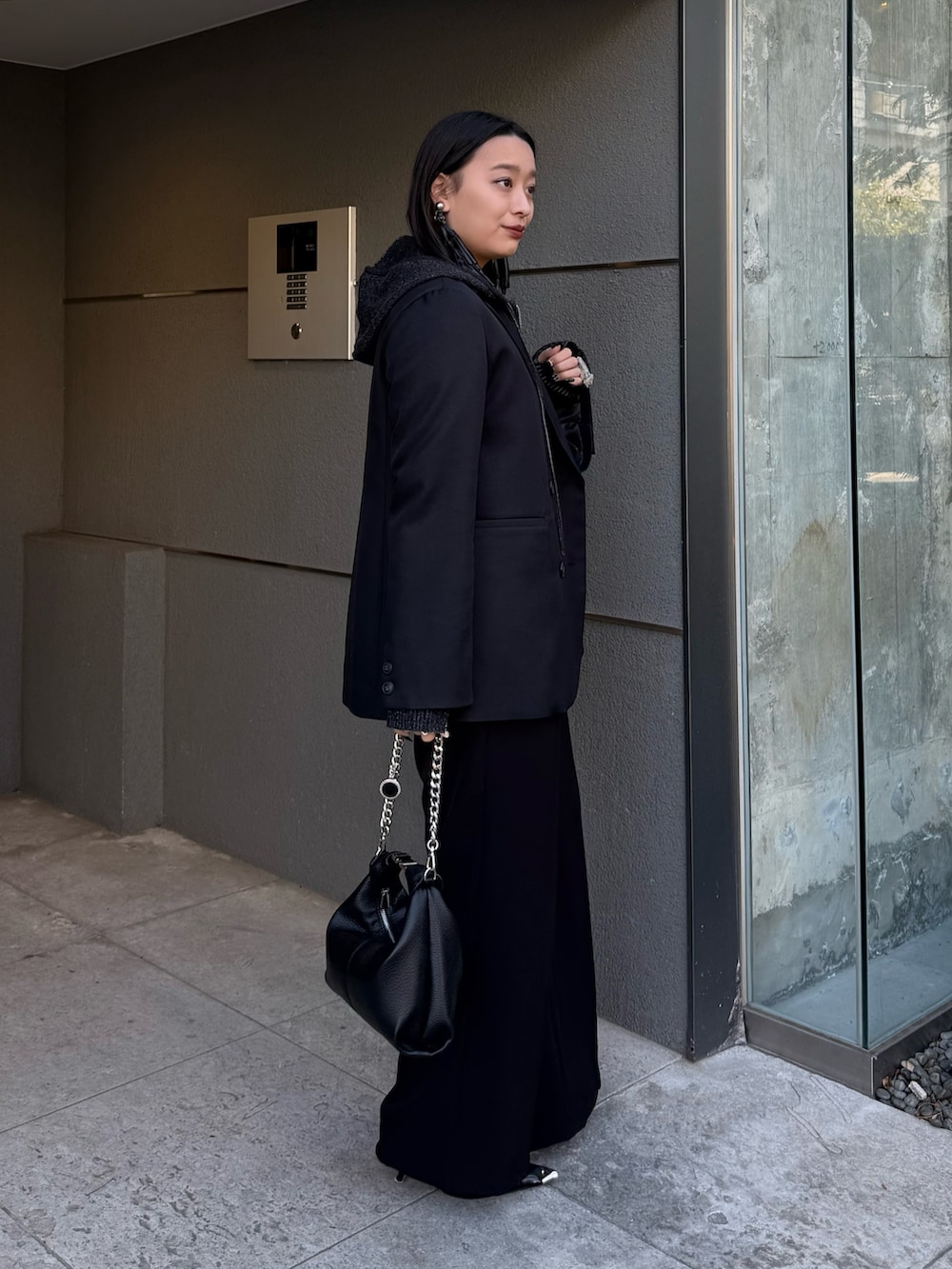 ブラック系のテーラードジャケット、ブラック系のニット/セーター、ブラック系のトートバッグを着用したレディースの冬コーディネートの2枚目の写真