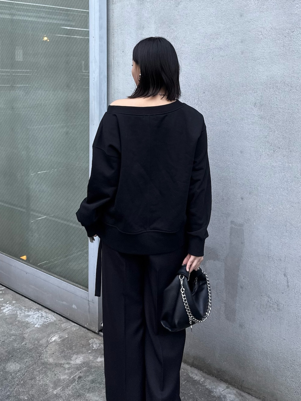 ブラック系のTシャツ/カットソー、ブラック系のスラックス、ブラック系のトートバッグを着用したレディースの冬コーディネートの5枚目の写真