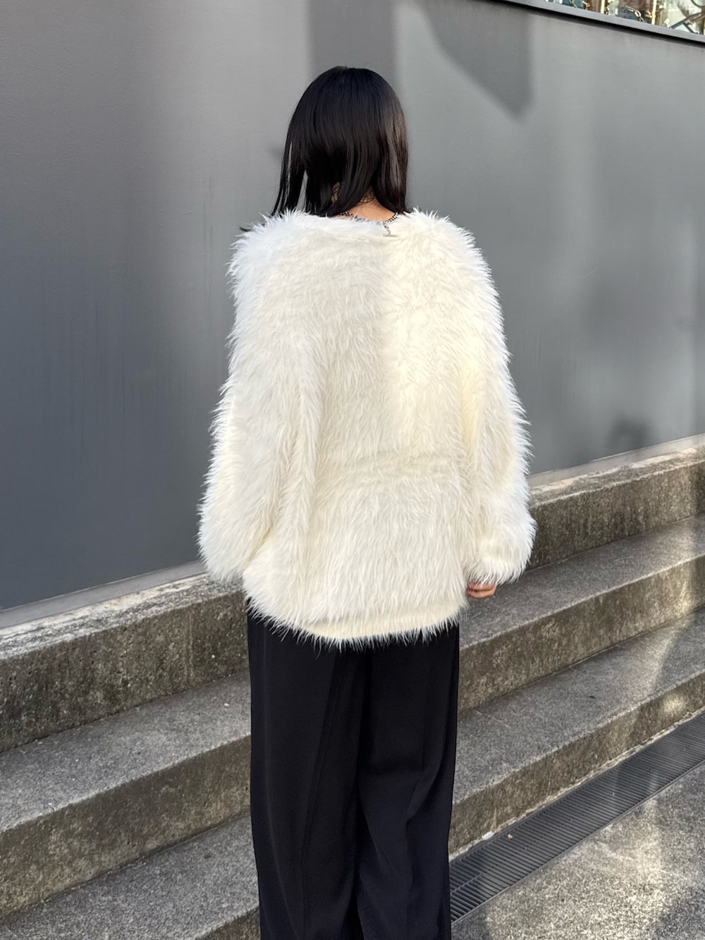 ブラック系のスラックス、ブラック系のブーツ、ホワイト系のカーディガン/ボレロを着用したレディースの夏コーディネートの4枚目の写真