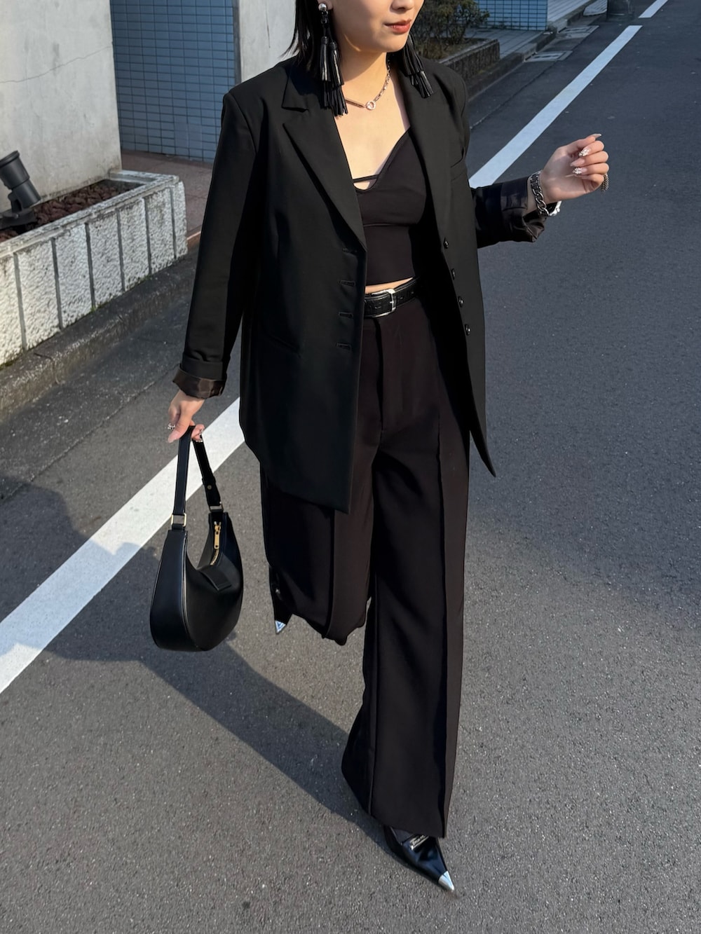 ブラック系のテーラードジャケット、ブラック系のスラックス、ブラック系のベルトを着用したレディースの冬コーディネートの2枚目の写真