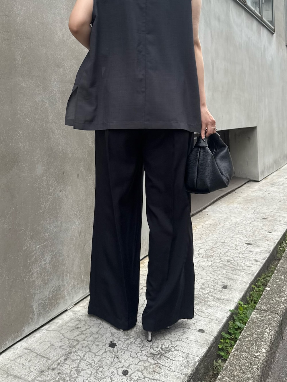 グレー系のベスト、グリーン系のタンクトップ、ブラック系のスラックスを着用したレディースの夏コーディネートの6枚目の写真