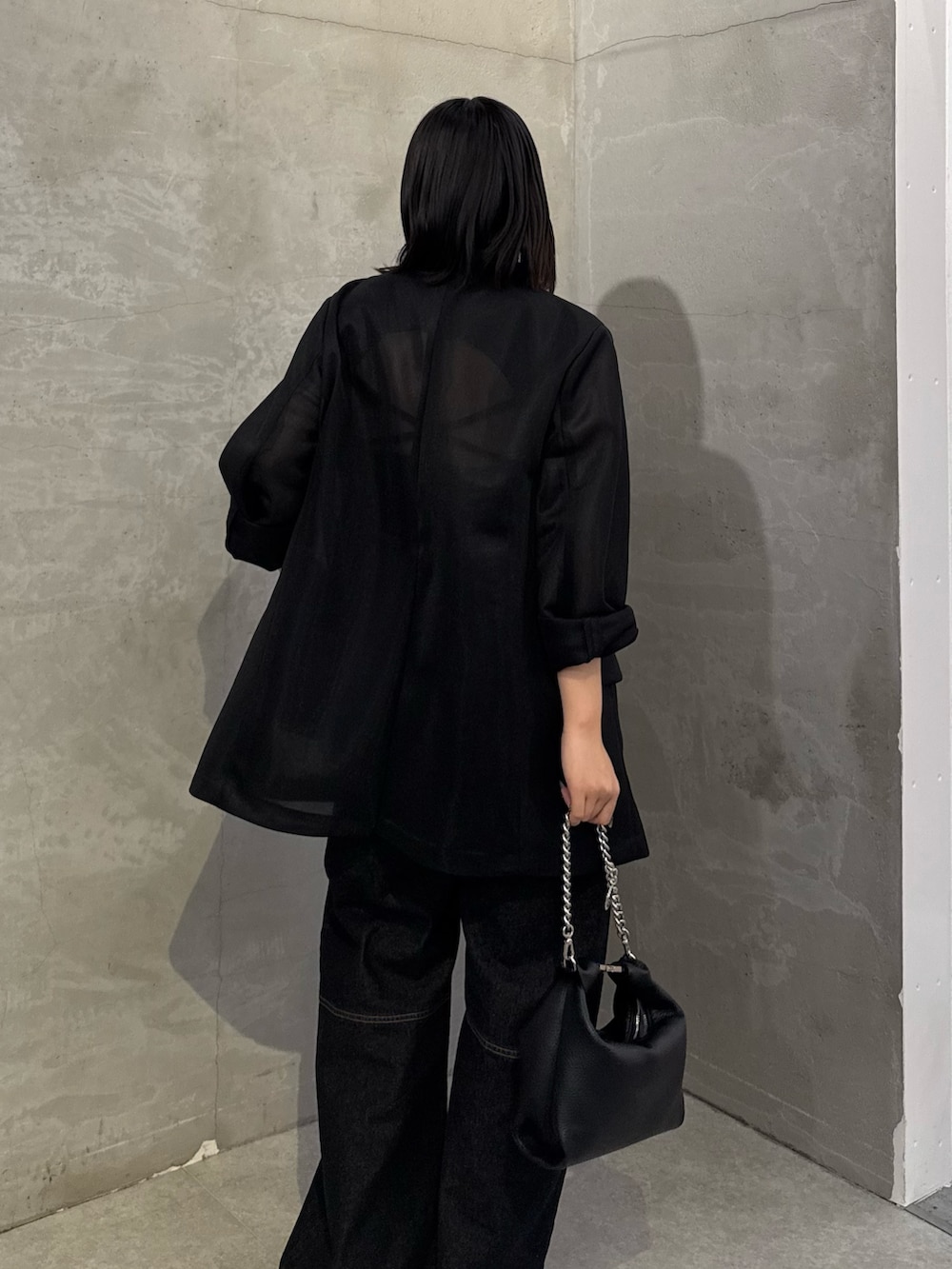 ブラック系のテーラードジャケット、ブラック系のデニムパンツ、ブラック系のトートバッグを着用したレディースの冬コーディネートの6枚目の写真