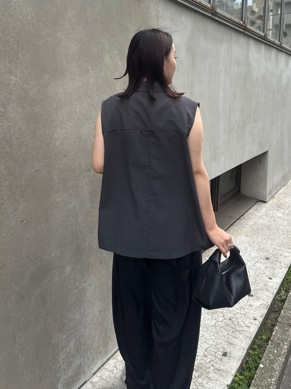 グレー系のベスト、グリーン系のタンクトップ、ブラック系のスラックスを着用したレディースの夏コーディネートの4枚目の写真