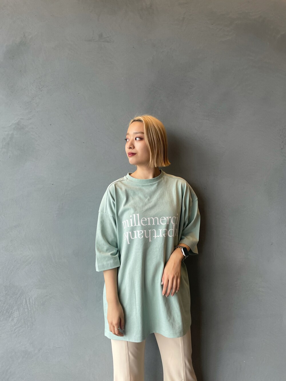 グリーン系のTシャツ/カットソー、ホワイト系のスラックス、ブラック系のスニーカーを着用したレディースの春コーディネートの2枚目の写真