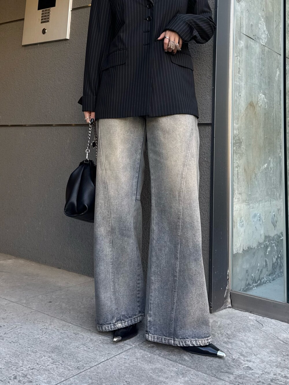 ブラック系のテーラードジャケット、ブルー系のデニムパンツ、ブラック系のトートバッグを着用したレディースの冬コーディネートの5枚目の写真