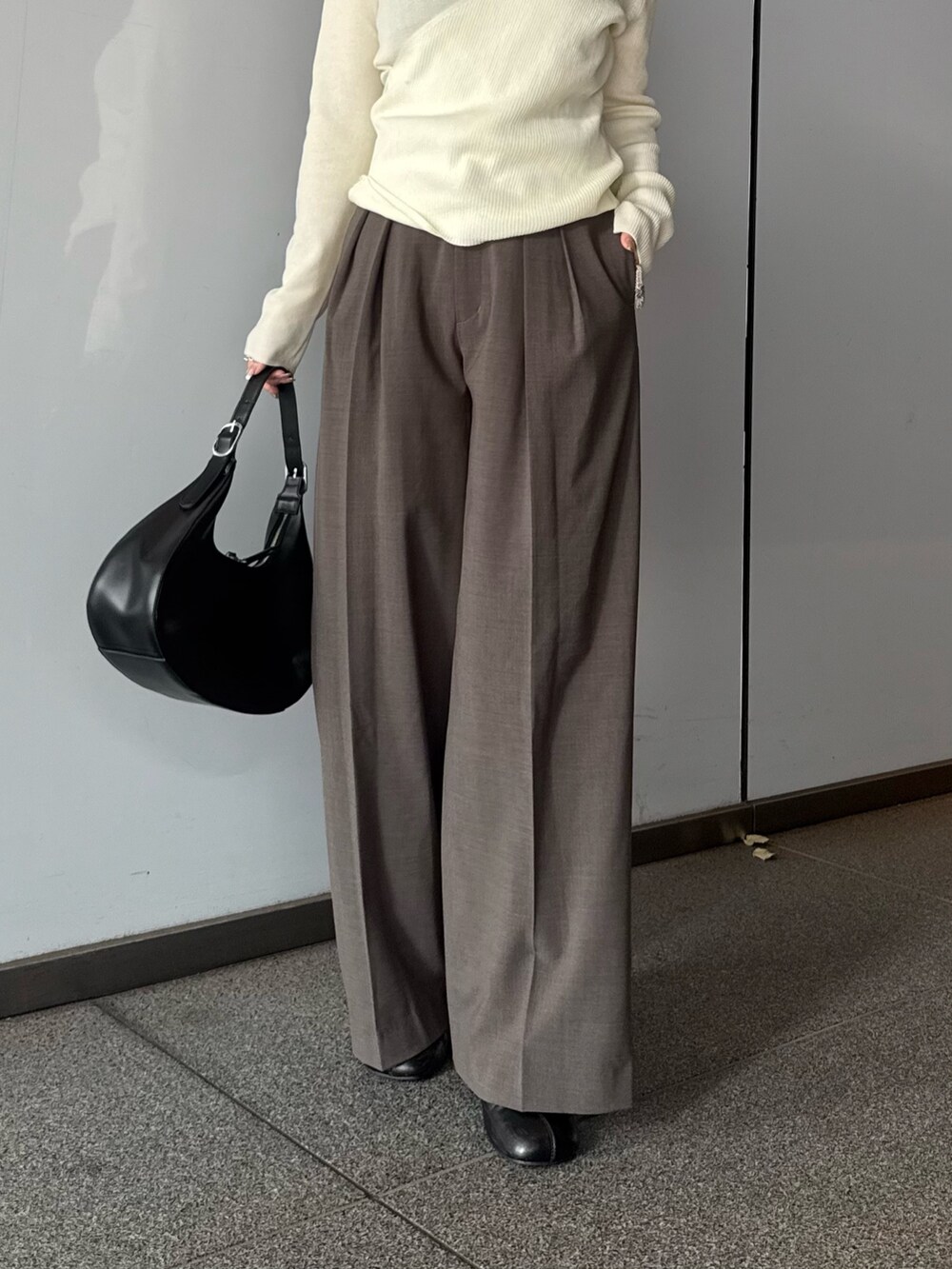 ホワイト系のニット/セーター、ブラウン系のスラックス、ブラック系のブーツを着用したレディースの夏コーディネートの4枚目の写真