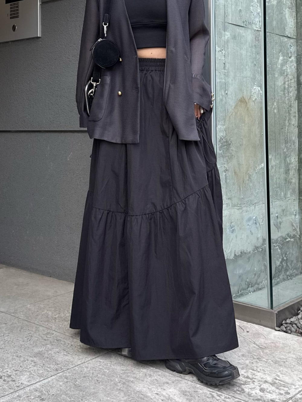 グレー系のテーラードジャケット、ブラック系のタンクトップ、ブラック系のスカートを着用したレディースの春コーディネートの6枚目の写真