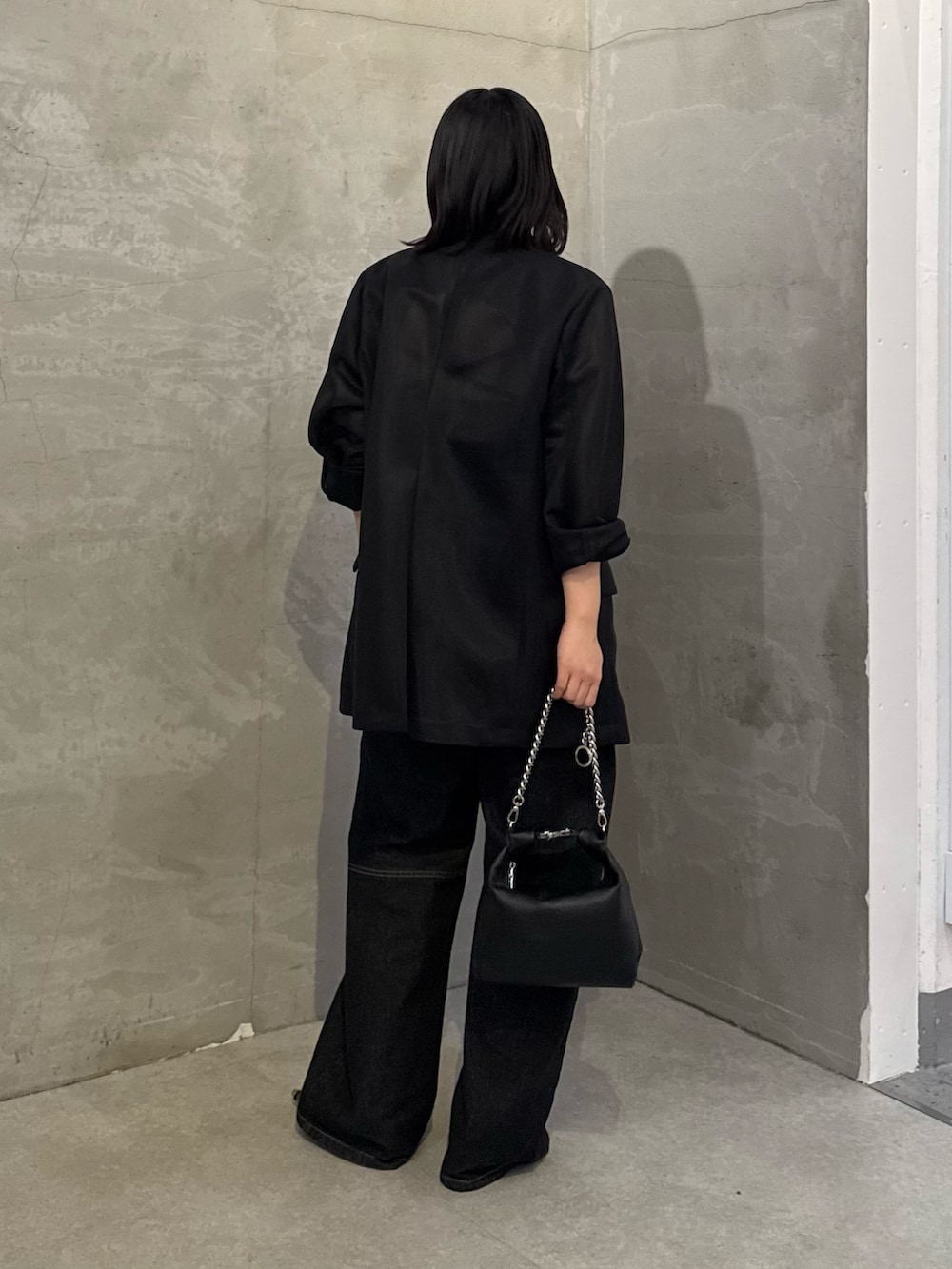 ブラック系のテーラードジャケット、ブラック系のデニムパンツ、ブラック系のトートバッグを着用したレディースの冬コーディネートの3枚目の写真