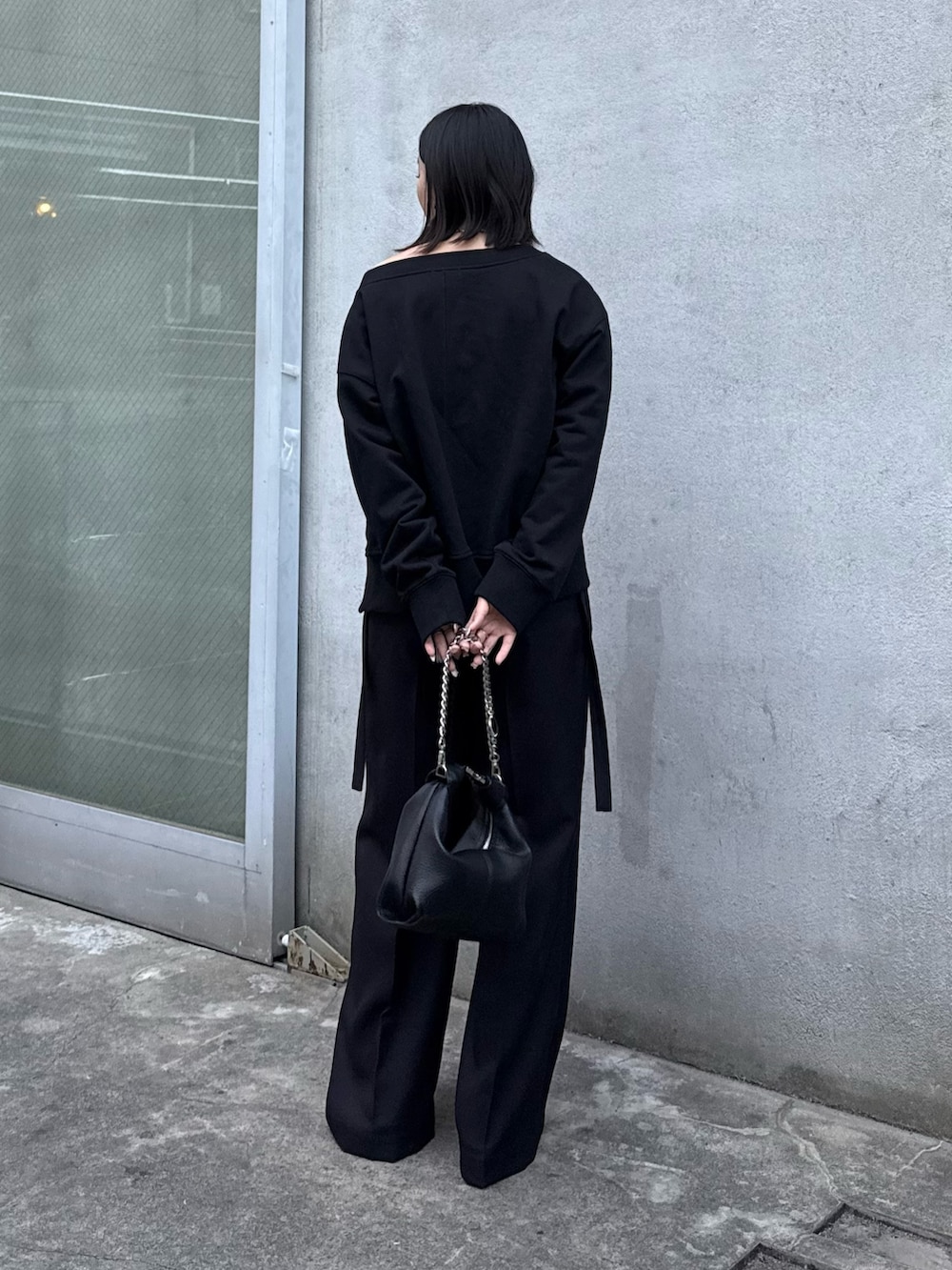 ブラック系のTシャツ/カットソー、ブラック系のスラックス、ブラック系のトートバッグを着用したレディースの冬コーディネートの3枚目の写真