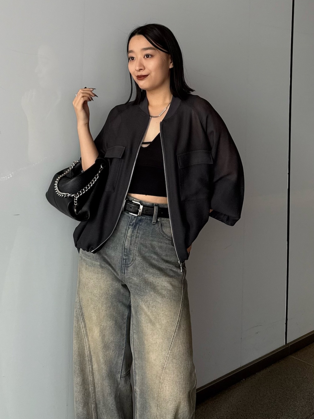 グレー系のブルゾン、ブルー系のデニムパンツ、ブラック系のトートバッグを着用したレディースの春コーディネートの3枚目の写真