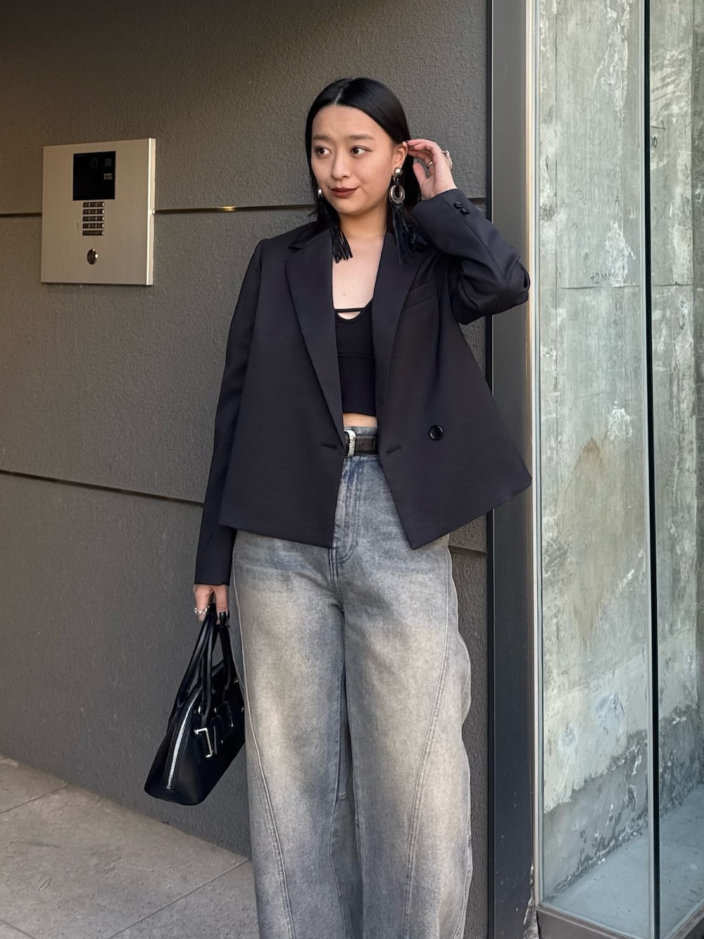 ブラック系のテーラードジャケット、ブルー系のデニムパンツ、ブラック系のショルダーバッグを着用したレディースの冬コーディネートの4枚目の写真