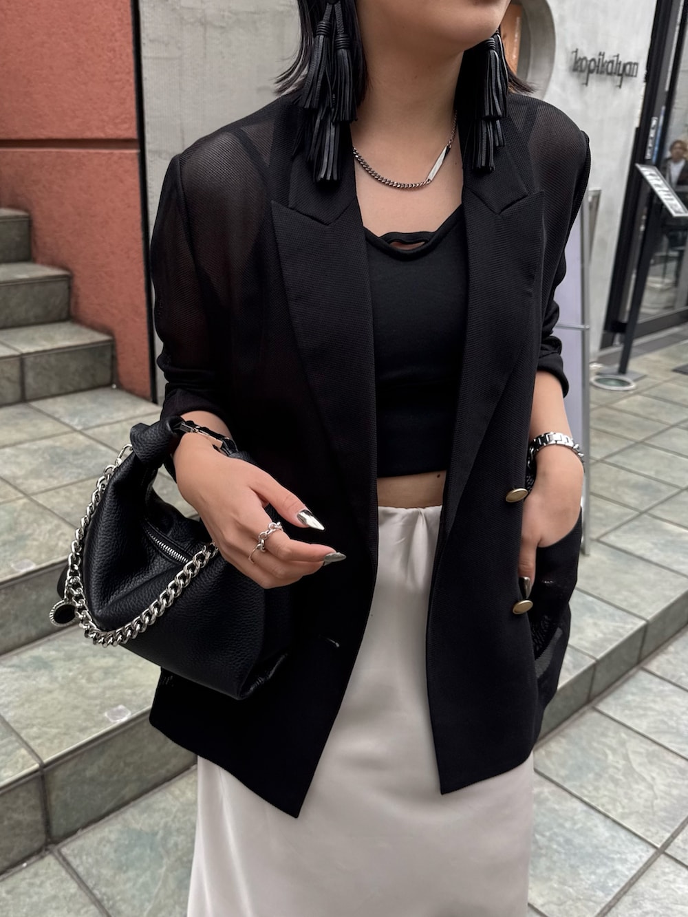 ブラック系のテーラードジャケット、ホワイト系のスカート、ブラック系のタンクトップを着用したレディースの春コーディネートの3枚目の写真